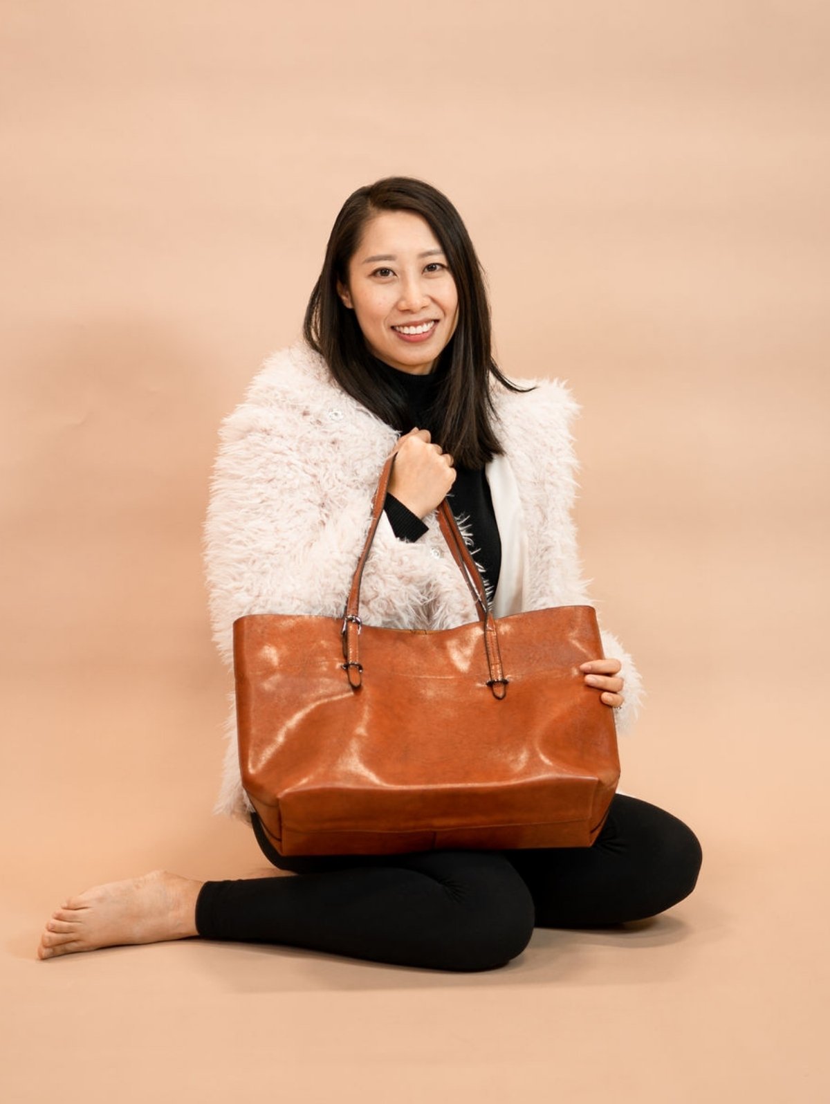 Wenwen sitting while holding the Road Less Traveled Tote